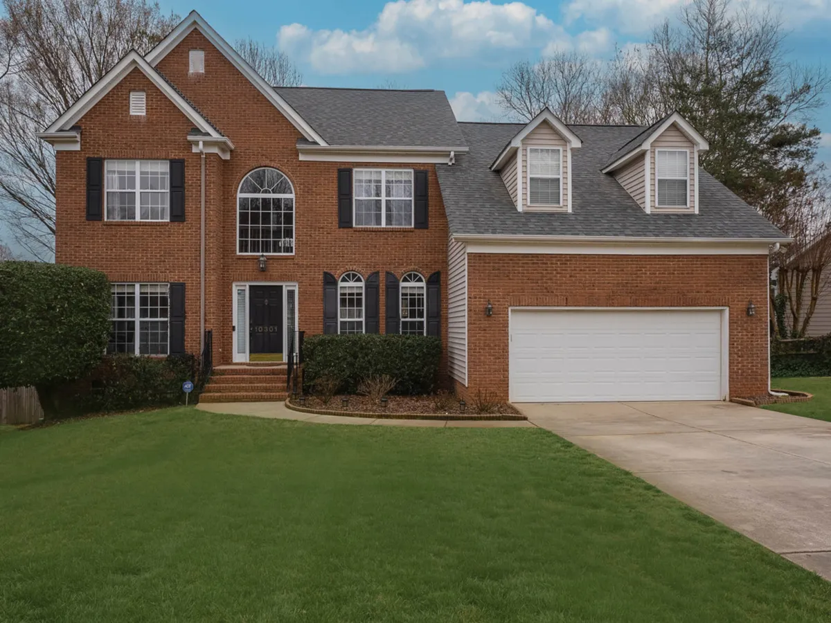 An exterior view of one of the homes, highlighting its inviting brick facade, large windows, front door, and manicured lawn. The image suggests ample space for arrivals and gatherings, and captures a sense of welcome on arrival.