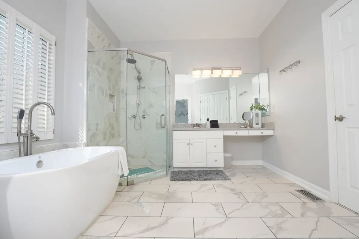 Here, a luxurious spa-inspired bathroom features a freestanding bathtub, glass shower enclosure, and a double vanity with a large mirror. The space is bright and calming, inviting guests to indulge in a tranquil soak or prepare for the day with ease.